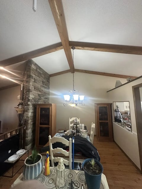 Modern living room with exposed beams, fireplace, chandelier, and home decor on shelving and tables